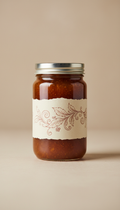 A perfectly centered, straight-on front view of a glass jar containing a rich, rustic copper-colored jelly. The jar has a...
