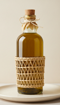A straight-on, perfectly centered product shot of a premium glass bottle of extra virgin olive oil, showcasing its rustic,...